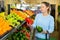 Middle-aged woman purchaser holding pepper in grocery store