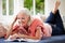 Middle Aged Woman Reading Magazine Lying On Sofa