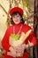 Middle-aged woman in red holding a paper bag with baguettes and herbs