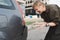 Middle-aged woman with a short haircut is shocked by the bumper damage on her car