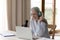 Middle-aged woman sit at desk with laptop talks into microphone