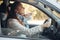 Middle aged woman sits in the car and complains on traffic situation - car stands on the verge of road in countryside