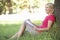 Middle Aged Woman Sketching In Countryside Leaning Against Tree