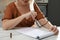 Middle aged woman solving sudoku puzzle at table in kitchen