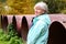 Middle aged woman standing outdoor in autumn near big old meal construction pipes