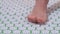 A middle-aged woman stands with one foot on an acupuncture massage mat. Close-up.