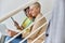 Middle aged woman with tablet sits with African-American colleague working on laptop on staircase