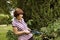 Middle-aged Woman Tackling Prickly Rose Bush With Secateurs.