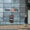 Middle aged woman walks past an Automatic Teller Machine from the HSBC bank advertising free cash withdrawals