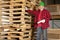 Middle aged working standing in front of wooden pallets