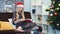 Middle close up of smart woman in Santa hat attentively reading book sitting on sofa at home