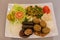 Middle Eastern plate with bulgur, salad, falafel, vine leaf dolma, grilled eggplant, hummus