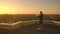 Middle plan: a male freelancer typing on a laptop keyboard at sunset overlooking the city while standing on the roof of