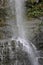 The middle section of Wailua Falls plummeting down a rocky cliff surrounded by lush vegetation in Hana, Maui