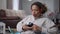 Middle shot of dissatisfied African American woman printing Remote working with label maker sitting on bag chair in home