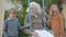 Middle shot of happy Caucasian brother and sister swinging grandfather on swings. Portrait of relaxed cheerful