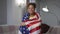 Middle shot of happy smiling African American woman posing with USA flag at home indoors. Portrait of proud young