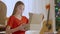 Middle shot portrait of excited surprised teenage girl opening New Year gift indoors. Happy Caucasian brunette teenager