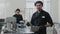 Middle shot portrait of young Caucasian man posing with bowl and whisk as blurred woman weighing eggs at background