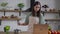 Middle shot of smiling young slim Asian woman mixing sauce in cooking pan looking at laptop screen. Portrait of