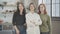 Middle shot of three confident beautiful Caucasian women standing indoors looking at camera. Charming young female