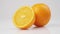 Middle shot of two fresh oranges rotate on its axis on a white table against white background, in isolation