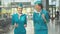 Middle shot of two joyful Caucasian women in stewardess uniform walking for departure in airport. Portrait of