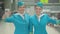 Middle shot of two positive confident Caucasian stewardesses in blue uniform saluting and smiling at camera. Portrait of