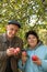 Middleaged couple stand under tree, hold apples