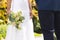 Midsection of african american bride with bouquet and groom standing in sunny garden