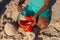 Midsection of african american girl playing with sand, pail and shovel while kneeling at beach