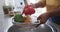 Midsection of african american woman rinsing peppers in kitchen sink, slow motion