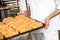 Midsection Of Baker Carrying Breads In Baking Tray