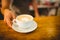 Midsection of barista serving heart shape frothy coffee at cafe