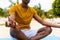 Midsection of biracial man practicing yoga meditation sitting on sunny beach