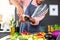 Midsection of biracial man wearing apron cooking dinner, seasoning vegetables in kitchen