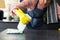 Midsection of biracial man wearing apron and rubber gloves cleaning countertop in sunny kitchen