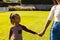 Midsection of biracial mother holding happy daughter\\\'s hands while standing on field in yard