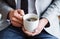 A midsection of businessman sitting in an office, holding a cup of coffee.