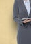 Midsection of businesswoman holding digital tablet against yellow background