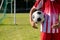 Midsection of caucasian male player wearing red jersey with soccer ball standing at playground