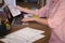 Midsection of caucasian woman sitting at table working at home, using laptop and holding paperwork