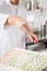 Midsection Of Chef Sprinkling Flour On Ravioli