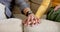 Midsection of diverse couple sitting on sofa holding hands at home, in slow motion