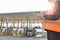 Midsection of female worker writing on clipboard while looking at truck entering in shipping yard