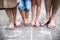 A midsection of legs of family with two small sons standing barefoot on a road.