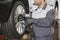 Midsection of male mechanic repairing car\'s wheel in workshop