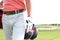 Midsection of man carrying golf club bag while walking at course