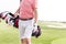 Midsection of man with golf club bag standing at course