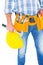 Midsection of manual worker holding hardhat and hammer